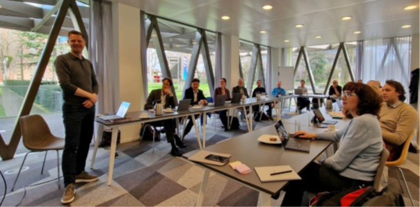 Kennis lab sessie - deelnemers aan tafels luisteren naar spreker Kennis lab sessie - deelnemers aan tafels luisteren naar spreker
