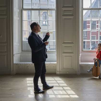 Groepje mensen, staand en zittend, luisterend naar spreker