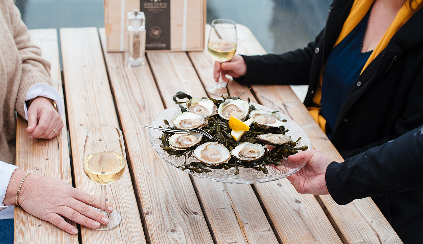 Schaal oesters wordt geserveerd met een glas witte wijn Schaal oesters wordt geserveerd met een glas witte wijn