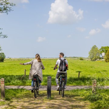 Stel fiets door het Friese landelijk gebied en steekt hand uit