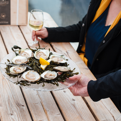 Schaal oesters wordt geserveerd met een glas witte wijn