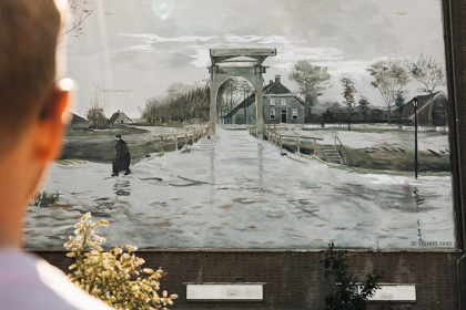 Man bekijkt muurschildering De Ophaalbrug van Vincent van Gogh op een oude silo (Groninger Museum). Design by Strakke Hand